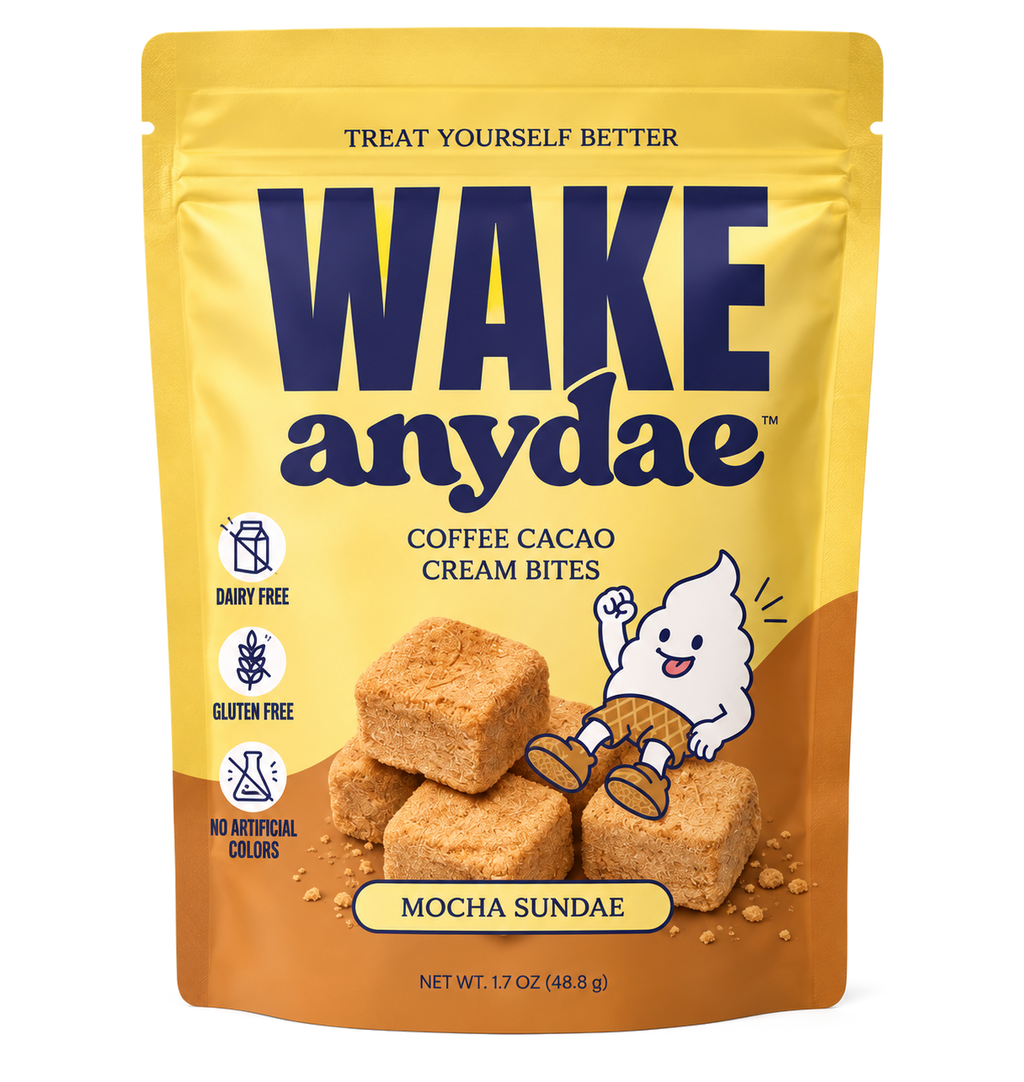 A stand-up pouch of Wake Anydae Coffee Cacao Cream Bites in Mocha Sundae flavor, shown on a plain white background. The packaging is primarily yellow on the upper half and brown on the lower half, with large navy brand text and an illustration of a white ghost sitting on a stack of tan cream bites.