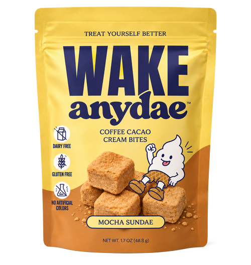 A stand-up pouch of Wake Anydae Coffee Cacao Cream Bites in Mocha Sundae flavor, shown on a plain white background. The packaging is primarily yellow on the upper half and brown on the lower half, with large navy brand text and an illustration of a white ghost sitting on a stack of tan cream bites.